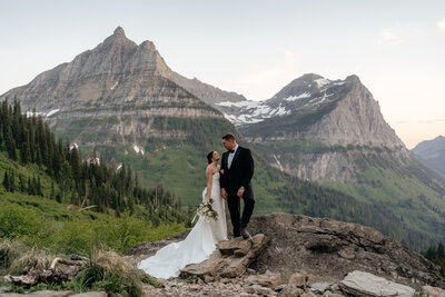A couple looks toward each other during sunset portraits in Glacier National Park.