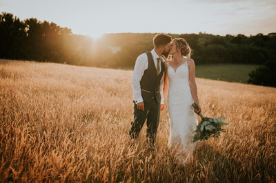 Couple kissing in field for wedding photos