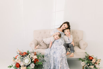 Image of Sacramento Maternity Photographer Kelsey Krall expecting baby sitting on couch with two sons