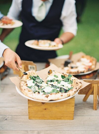 Fresh pizza being served to guests at outdoor party