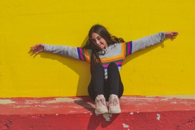 teen girl sitting in front of yellow wall