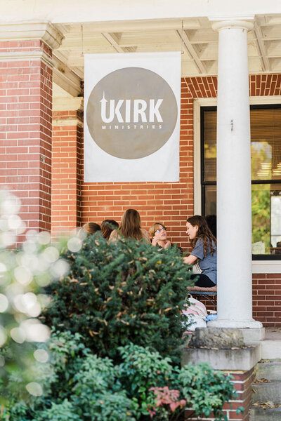 front porch of large historic brick house with UKIRK banner hanging from roof