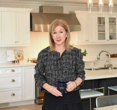 realtor standing in kitchen holding a mug