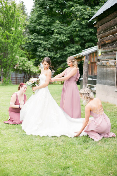 A woman wearing a wedding dress, being waited on by her bridesmaids.