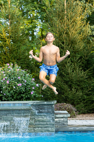 Boy in mid-air posing while jumping in pool