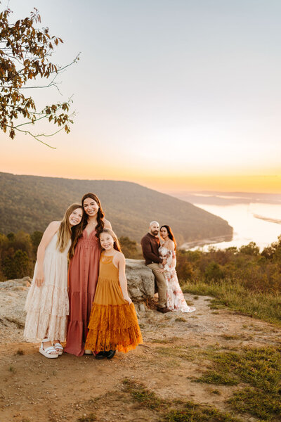 family standing together on cliffside at golden hour