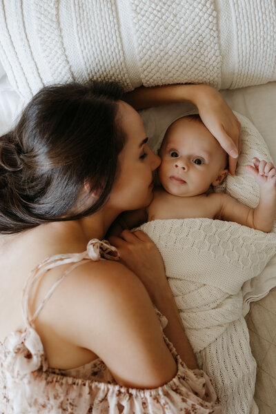 mom cuddling newborn baby in nursery
