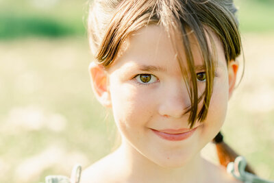 Closeup photo of a young girl with bangs covering her eyes and braids by Chicago Family Photographer Kristen Hazelton