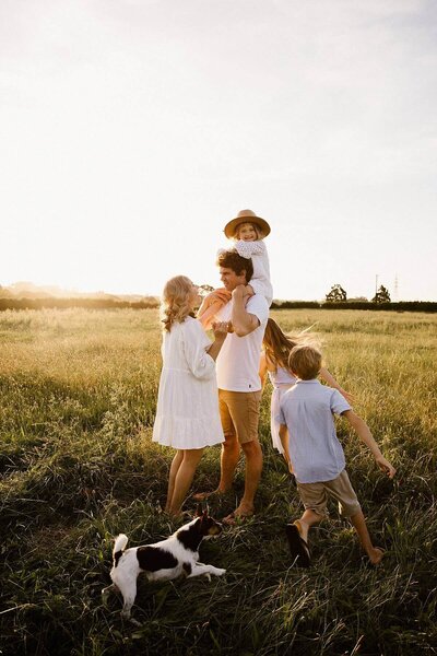 The Johnson family and their pet running around a field during their family photoshoot