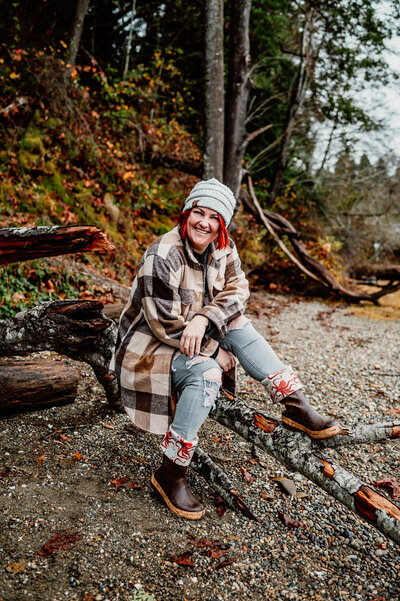 Aim True Photography, a red headed girl, sitting on a log on a PNW beach