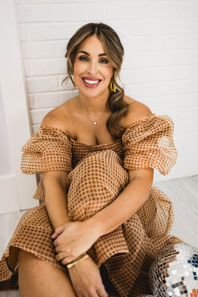woman sitting on the floor in a loose dress while smiling