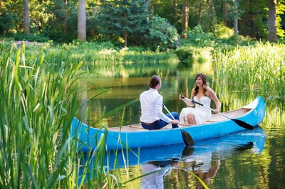 a bride and groom sit in a bright blue canoe on a sunny day at bridal veil lakes