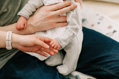 Closeup of newborn baby's hand as he holds his mother's fingers, in their Somerville living room