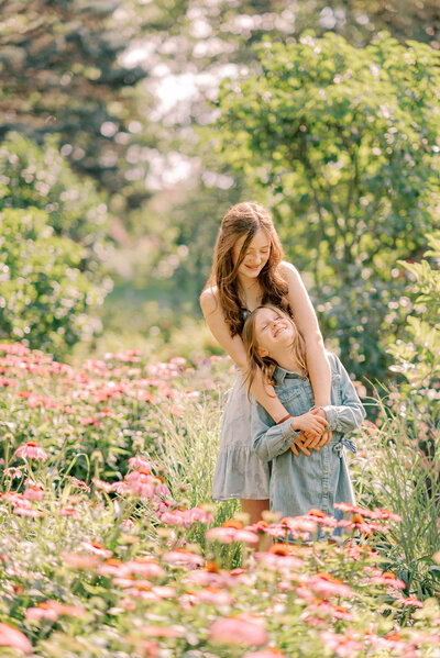 Two sisters hugging in a garden full of pink flowers for their Chicago family portraits
