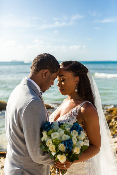 bride and groom share an embrace in front of a beach in Cancun Mexico