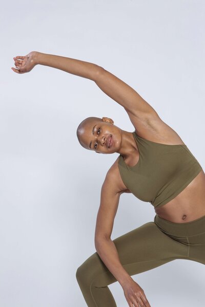 Woman in green workout clothes stretching to the left