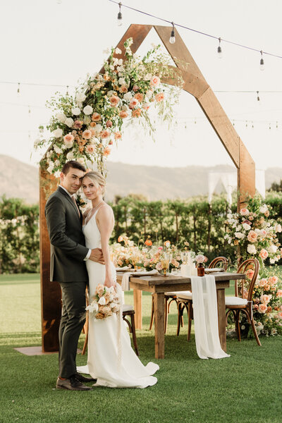 You can't miss this bride and groom standing in front of their magnificent wedding arbor full of fresh flowers.