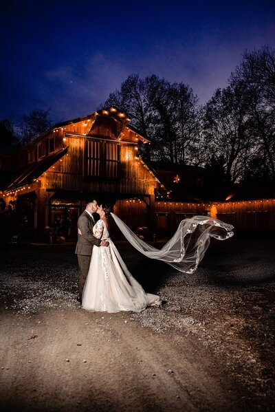 Bride and groom standing outside of Copper Ridge wedding venue at sunset