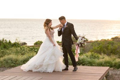 Bride and groom posing on a lookout point over the ocean in Santa Barbara, California