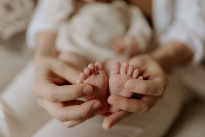 A woman's hands holding a baby's feet.