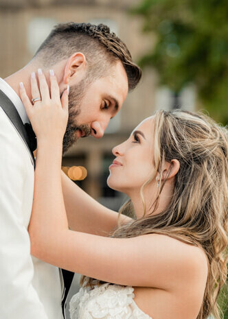 A bride gently holding her groom’s face as they share an intimate moment on their wedding day, captured by a UK wedding photographer.