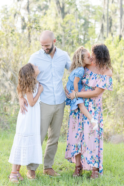Family of four embrace and look lovingly at each other outdoors