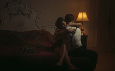 Intimate moment of a couple embracing in a dark room, softly lit by a lamp, capturing a peaceful and romantic connection in a cozy, serene setting