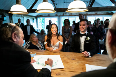 Bride and groom sit together as the ketubah is signed