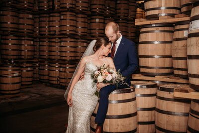 photo of bride and groom  with whiskey barrels