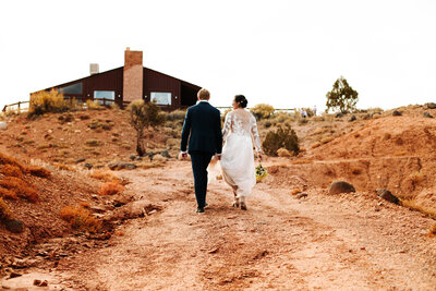 Bride and groom walking uphill in the desert at Capitol Reef National Park near Moab, Utah.