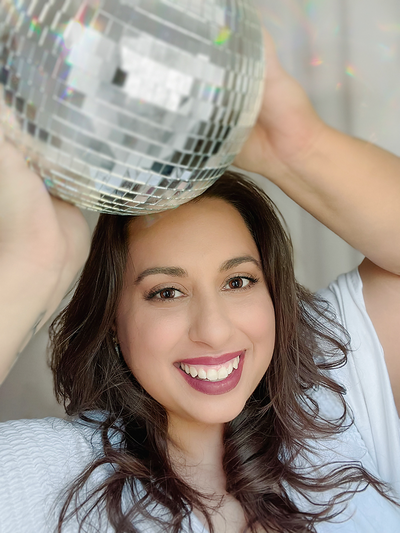 Brand expert Lena Gosik-Wolfe smiling and holding glittering disco ball above her head.