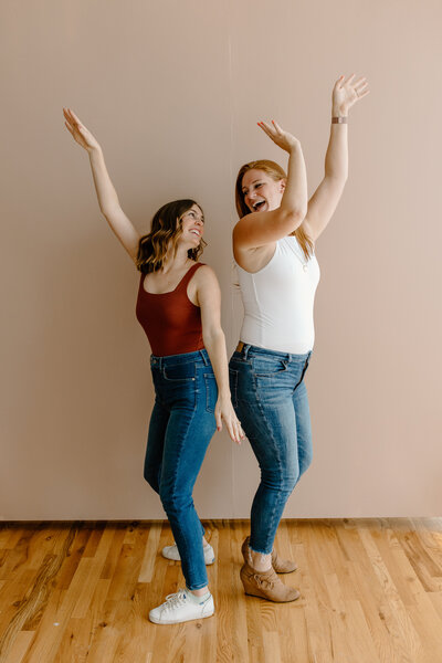 Bridget and Alicia turned away from each  other looking over their shoulders to face one another with their arms waving in the air.