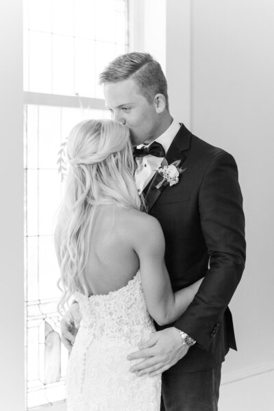 Black and white photo groom kissing bride's head