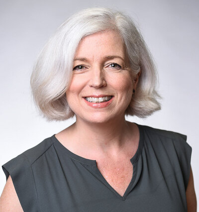 Professional photo of woman with white hair in studio with grey backdrop