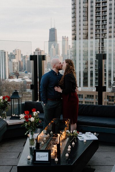 newly engaged people kiss on a chicago rooftop
