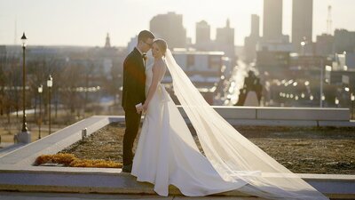 Sunset photo session at Des Moines, IA courthouse.Couple in wedding attire standing  with Des Moines Skyline behind them.
