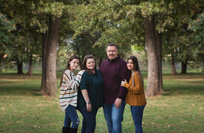 family-of-4-with-two-teens-at-park-in-arlington-tx-wearing-green-maroon-and-yellow