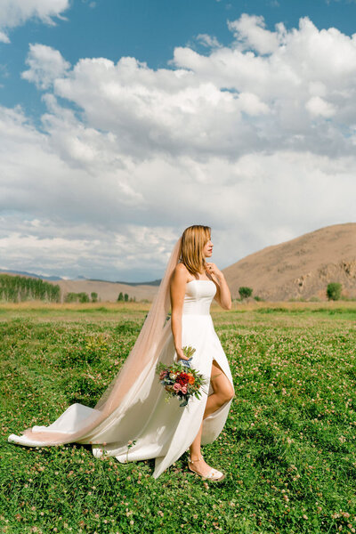 bride holding her bouquet and walking in a green field