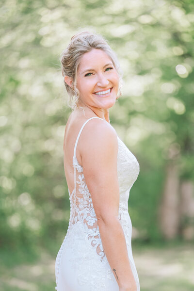 A smiling blonde bride in a  garden enjoying her Raleigh wedding photography bridal portrait session by JoLynn Photography