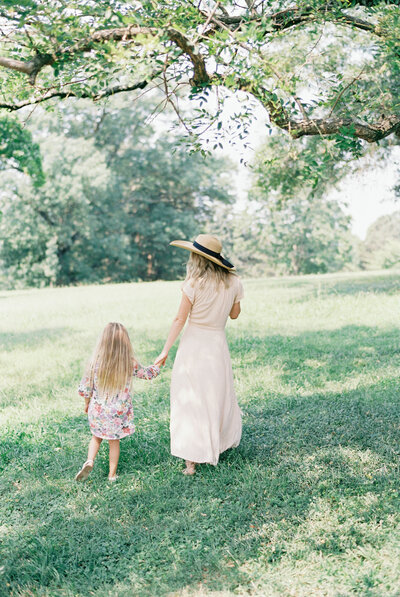 Mom in a hat and little girl walking holding hands by richmond family photographer