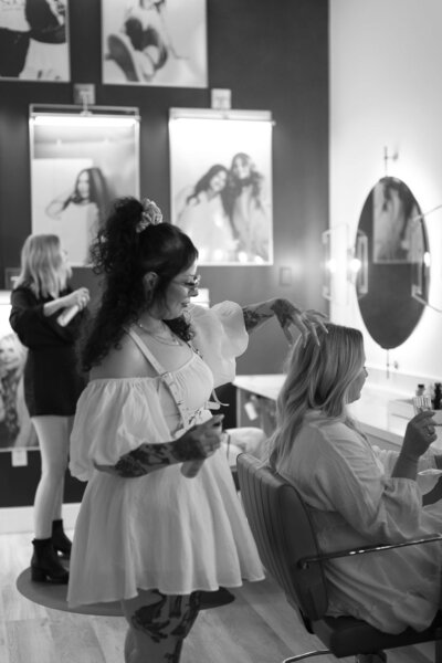 SoCo Dry Bar stylist performing a professional blowout on a smiling client in the salon.