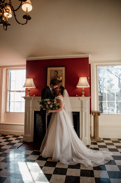 Bride and Groom standing in front of fireplace kissing, Salem Wedding