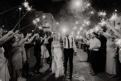 Bride and groom celebrating after they walk out to sparklers full of excitement in downtown wichita kansas at Distillery 244 Old Town wedding venue