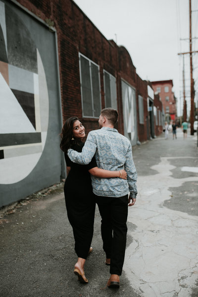 engagement session downtown with young couple walking along the mural lined streets in downtown jersey city waterfront