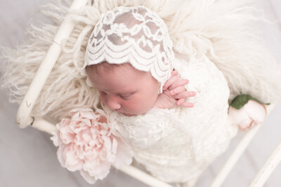 newborn baby girl in  white lace wrap with headband