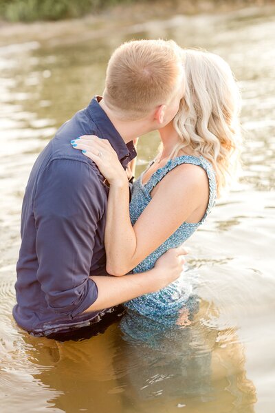 Engaged couple kiss while standing waist-deep in  Lake Minnetonka.