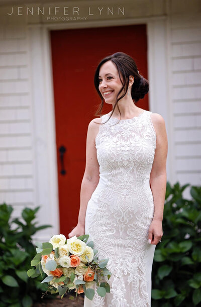 bride in front of door with flowers looking off to side