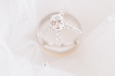 A stunning diamond ring with a gold wedding band wrapped in a white veil by destination wedding photographer, JoLynn Photography