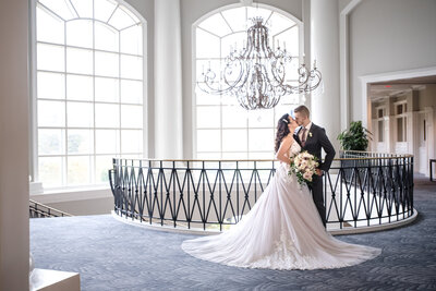 Bride and groom kissing at chandelier at top of stairs at the Ballantyne Hotel by Charlotte wedding photographers DeLong Photography