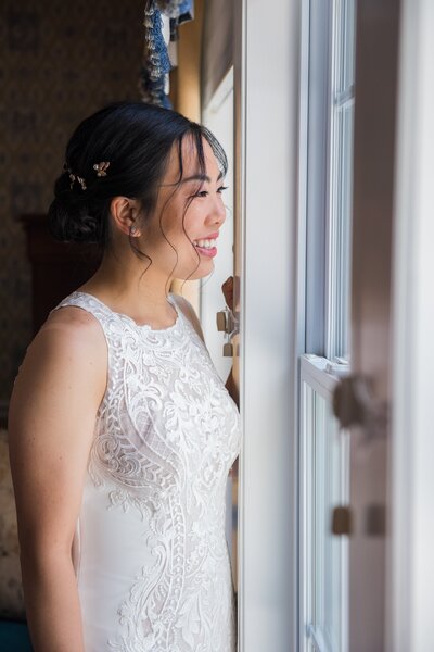Bride in dress looking out window